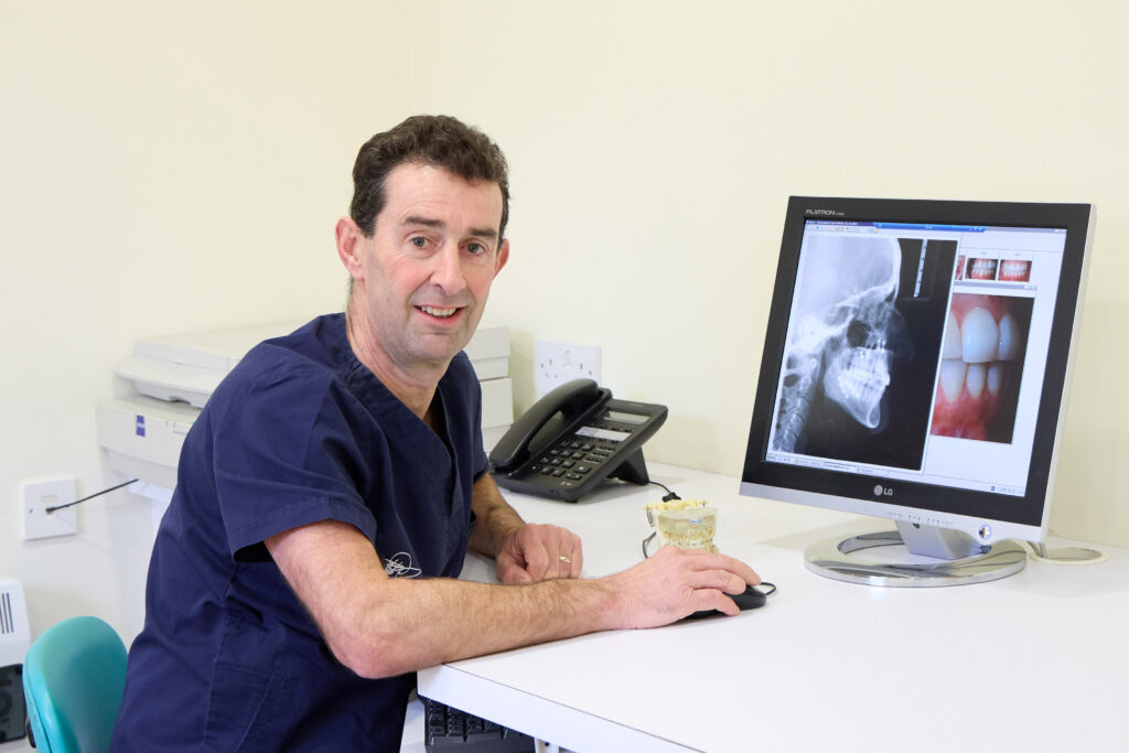 Picture of an Orthodontist in a clinic reviewing dental X-rays and images on a computer screen