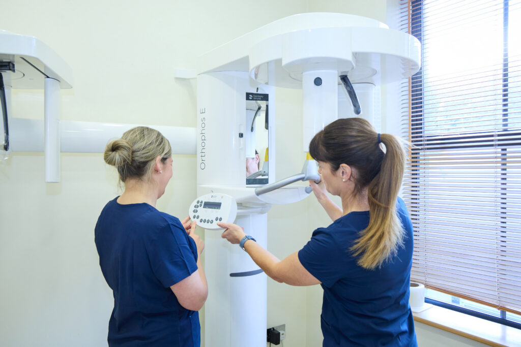 Picture of two orthodontic assistants in navy scrubs using an orthodontic x-ray