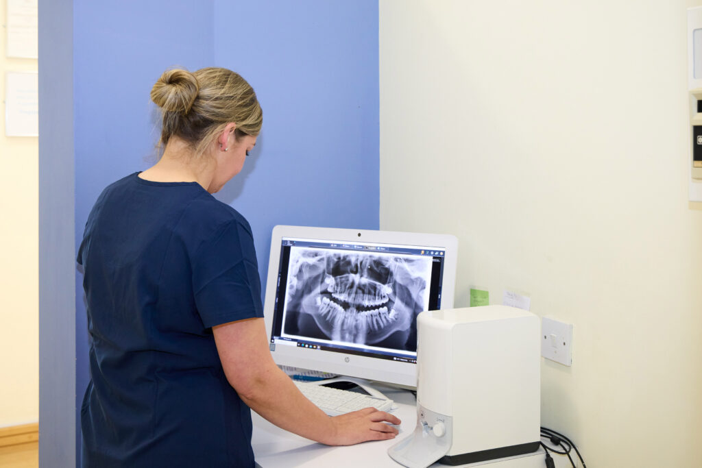 Picture of an orthodontic assistant in navy scrubs viewing an x-ray of a jaw