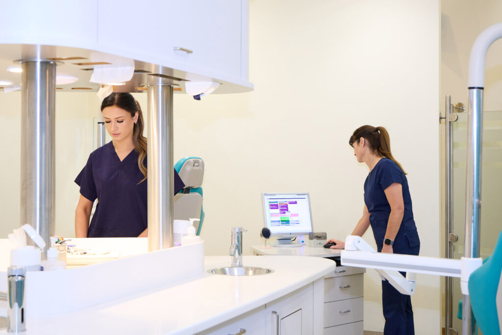 Picture of two orthodontic assistants in navy scrubs working in an orthodontic room