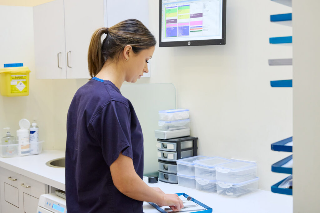 picture of an orthodontist in navy scrubs picking up some metal tools